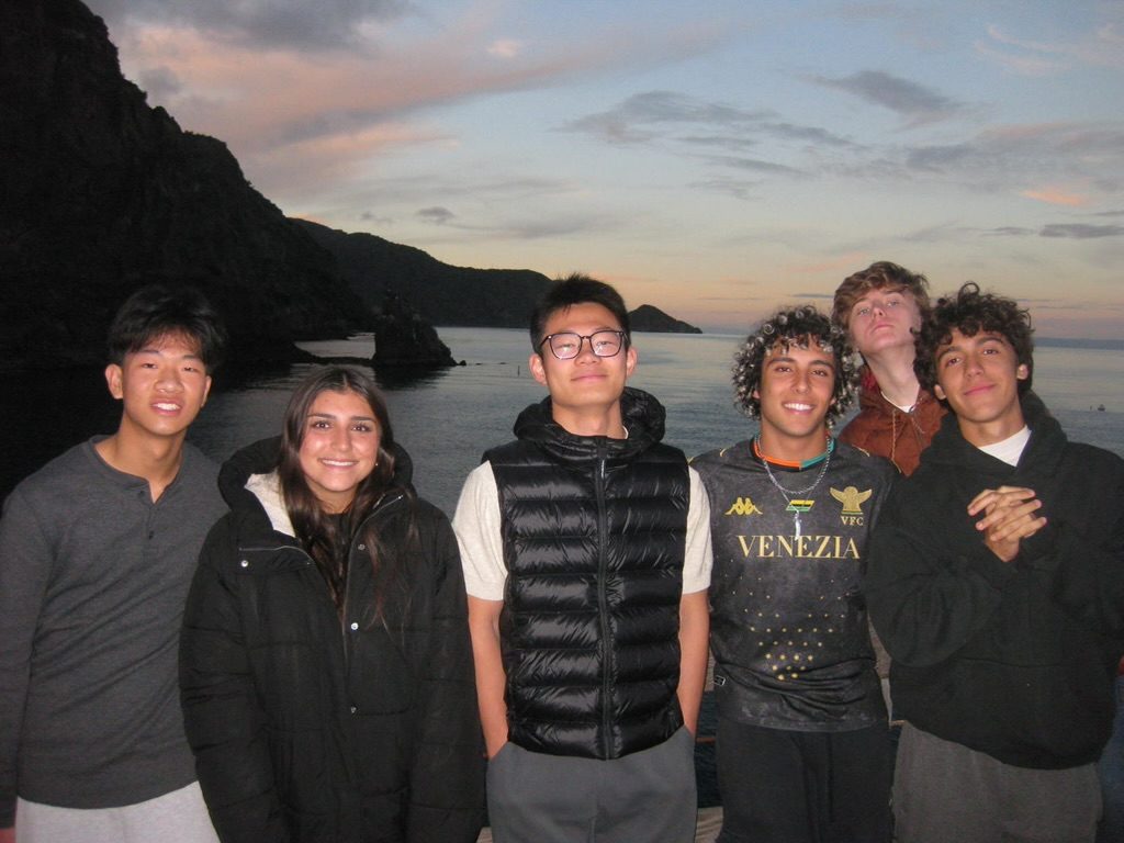 Friends posing together by the sea at sunset
